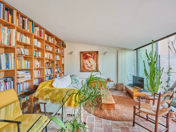 Intérieur d'une maison de ville à Marseille, avec bibliothèque, salon lumineux et plantes.