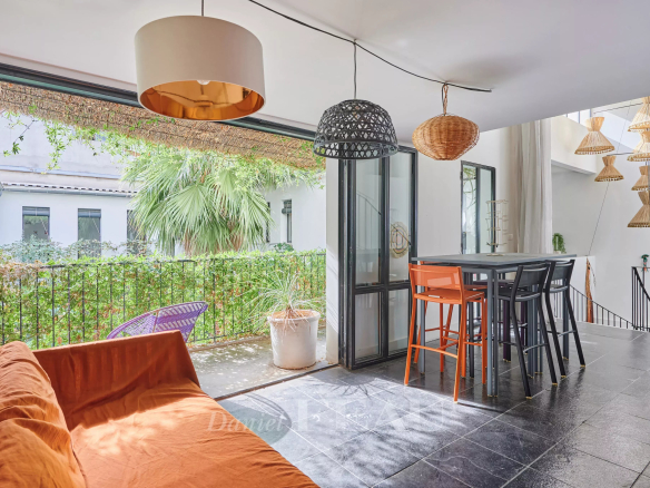 Interior of a house in Marseille 7th district with living room, high table and view of a green patio.
