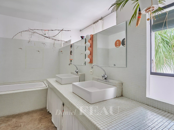 Modern bathroom with bathtub and double sink, mosaic tiled walls.
