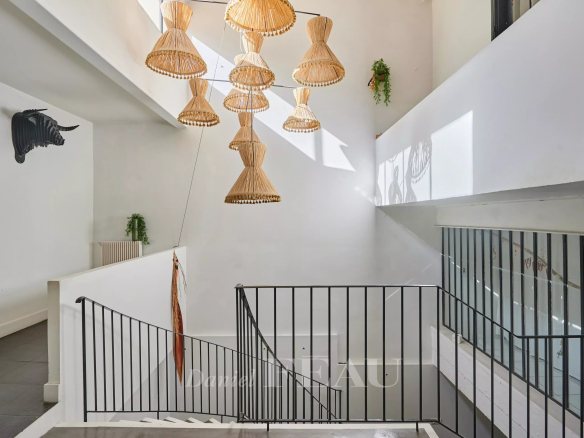 Interior of a house in Marseille 7th district with a staircase and wicker pendant lights.