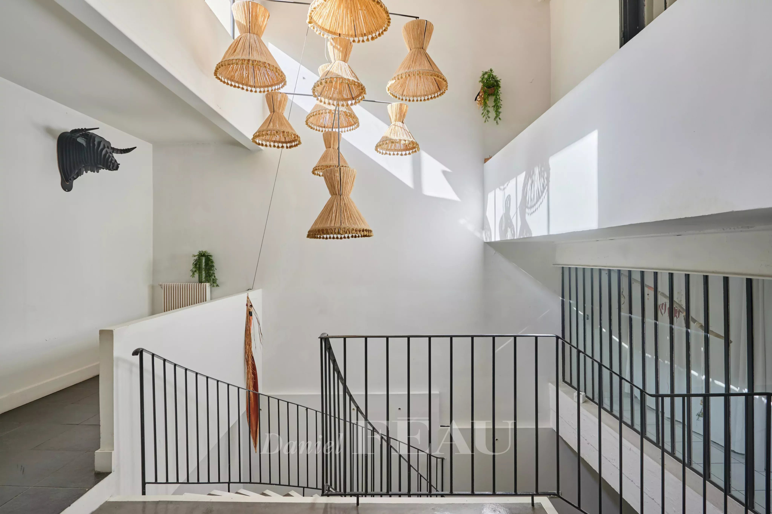 Modern interior in Marseille 7th arrondissement Interior of a house in Marseille 7th district with a staircase and wicker pendant lights.