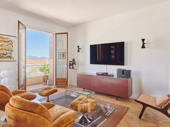 Salon lumineux d'un appartement rénové avec vue sur l'extérieur, mobilier moderne et télévision.