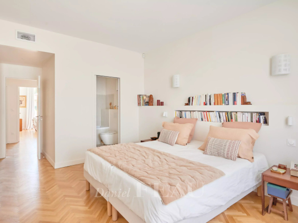 Chambre d'un appartement rénové avec un lit double et des étagères, éclairée par la lumière naturelle.