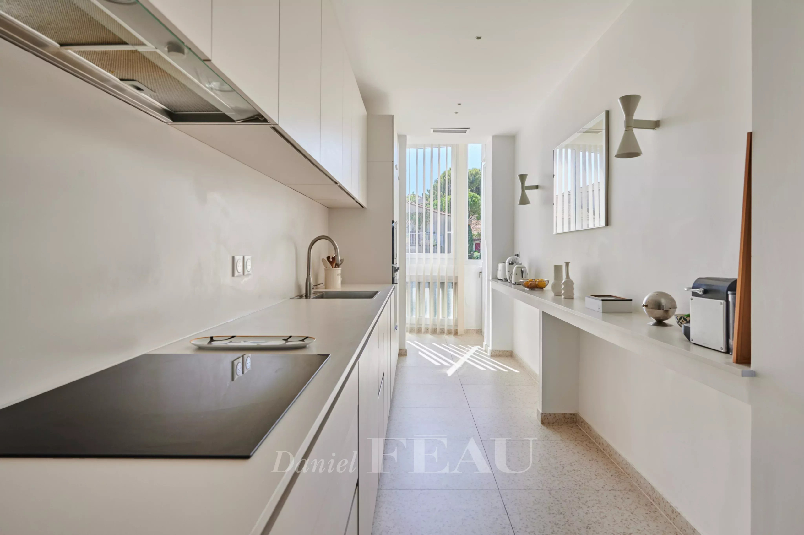 Cuisine rénovée à Marseille 8ème Cuisine moderne et lumineuse d'un appartement rénové à Marseille 8ème, avec plans de travail clairs et fenêtres.