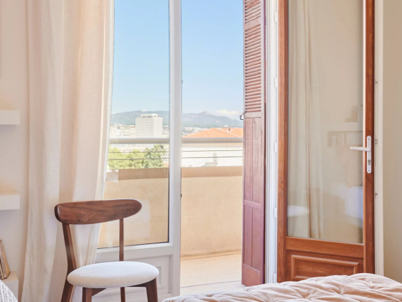 Chambre d'appartement rénové à Marseille avec porte-fenêtre donnant sur le balcon.