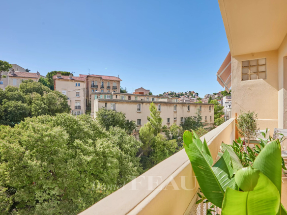 Vue depuis le balcon d'un appartement rénové à Marseille, avec des arbres et des bâtiments en arrière-plan.