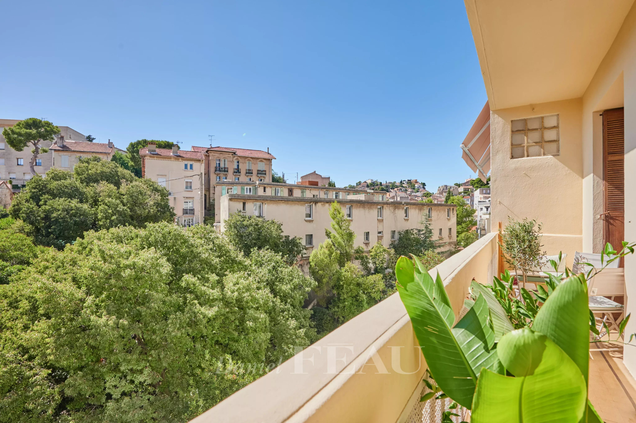 Balcon d’un appartement à Marseille 8ème Vue depuis le balcon d'un appartement rénové à Marseille, avec des arbres et des bâtiments en arrière-plan.