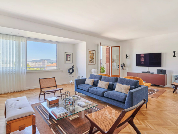 Salon lumineux d'un appartement rénové avec canapé et table basse, vue sur la ville de Marseille.