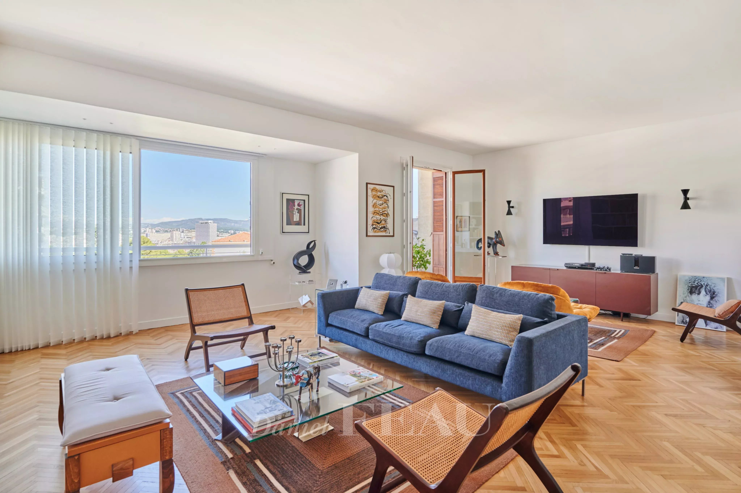 Salon d’un appartement rénové à Marseille 8ème Salon lumineux d'un appartement rénové avec canapé et table basse, vue sur la ville de Marseille.