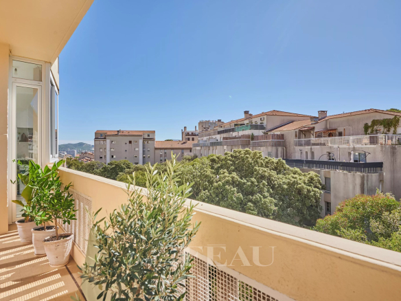Balcon d'un appartement rénové avec vue sur des bâtiments et des arbres à Marseille 8ème.