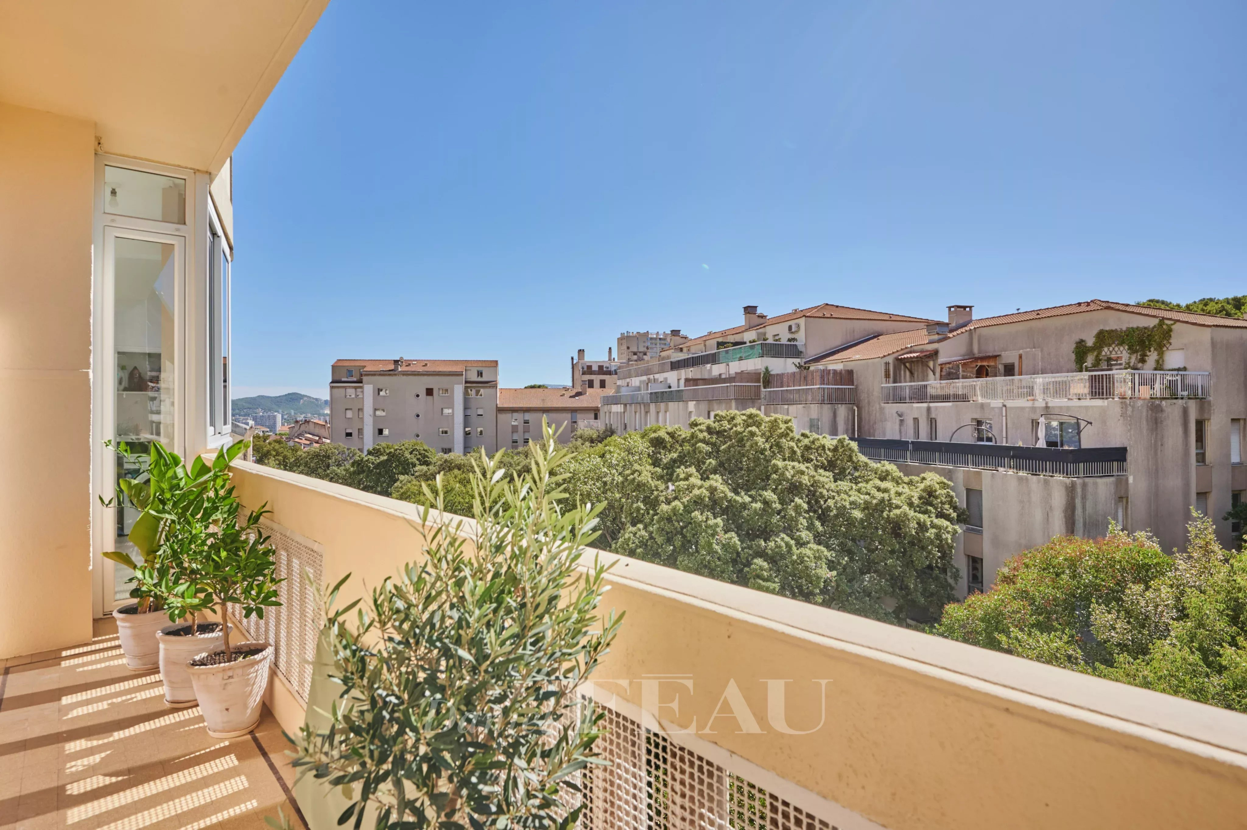 Balcon d’un appartement à Marseille 8ème Balcon d'un appartement rénové avec vue sur des bâtiments et des arbres à Marseille 8ème.