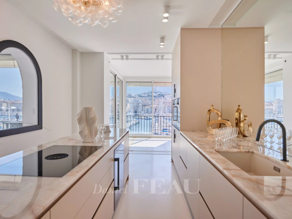 Cuisine moderne avec vue sur le Vieux-Port de Marseille depuis un appartement rénové.