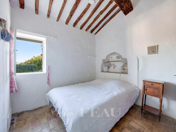 Chambre d'une bastide en pierres avec plafond à poutres apparentes, située au Beausset.
