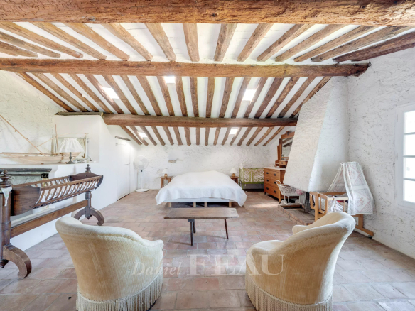Intérieur d'une bastide en pierres avec poutres apparentes et mobilier ancien.
