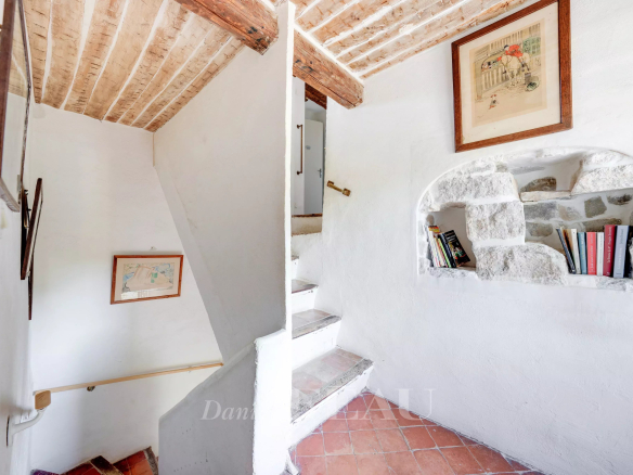 Escalier intérieur d'une bastide en pierres avec murs blancs et éléments décoratifs.