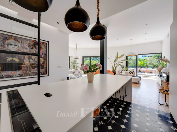 Intérieur d'un appartement moderne avec cuisine ouverte et îlot central, décoré de plantes et d'œuvres d'art.