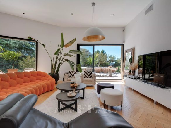 Salon lumineux d'un appartement avec canapé orange et vue sur une terrasse.