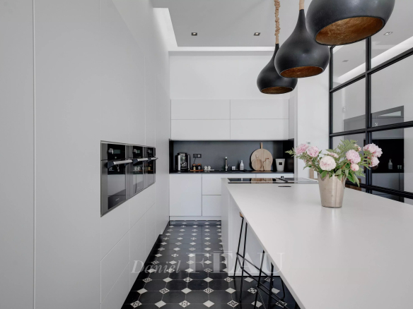 Cuisine moderne avec îlot central et appareils intégrés dans un appartement de standing.