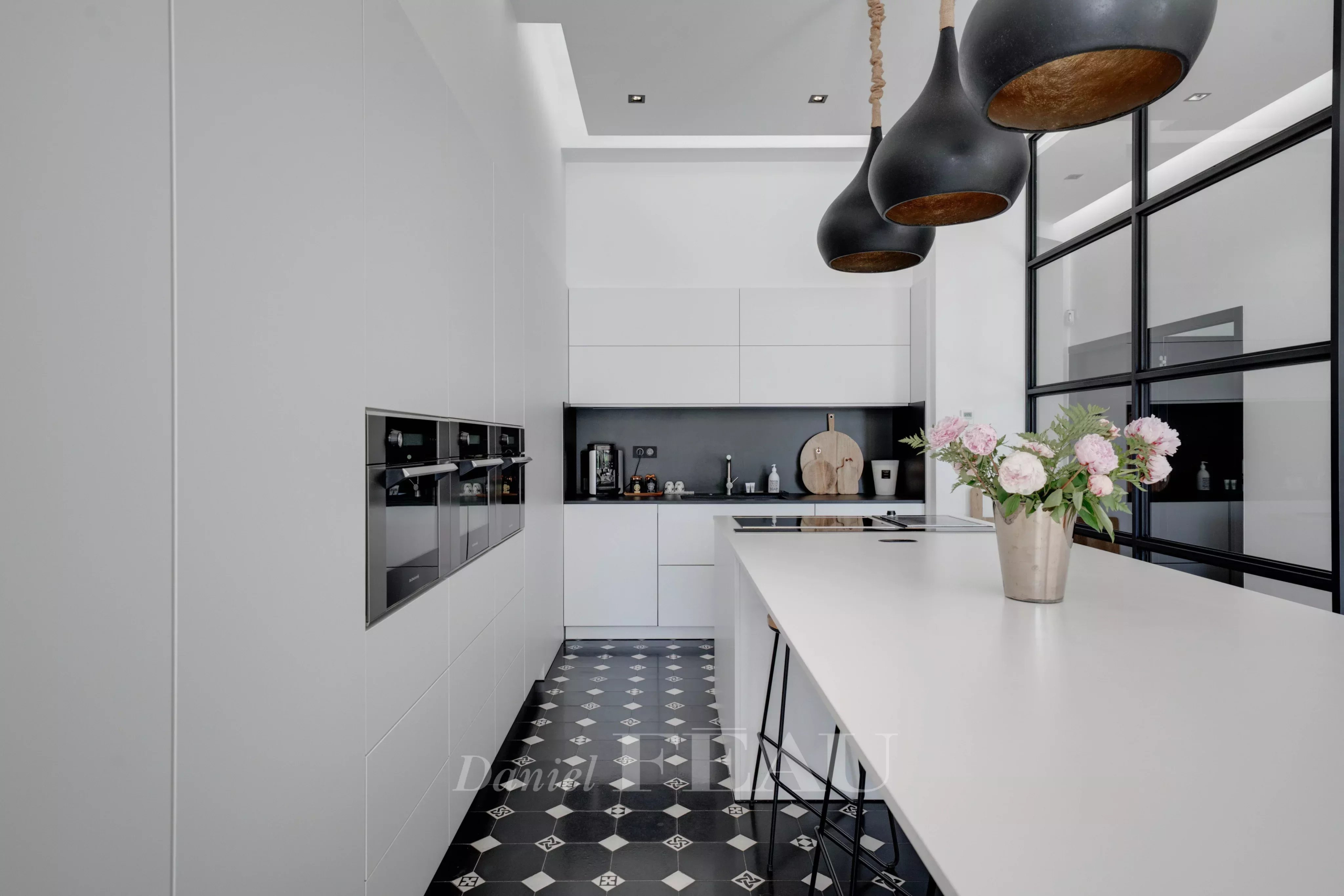 Cuisine moderne avec îlot central et appareils intégrés dans un appartement de standing.