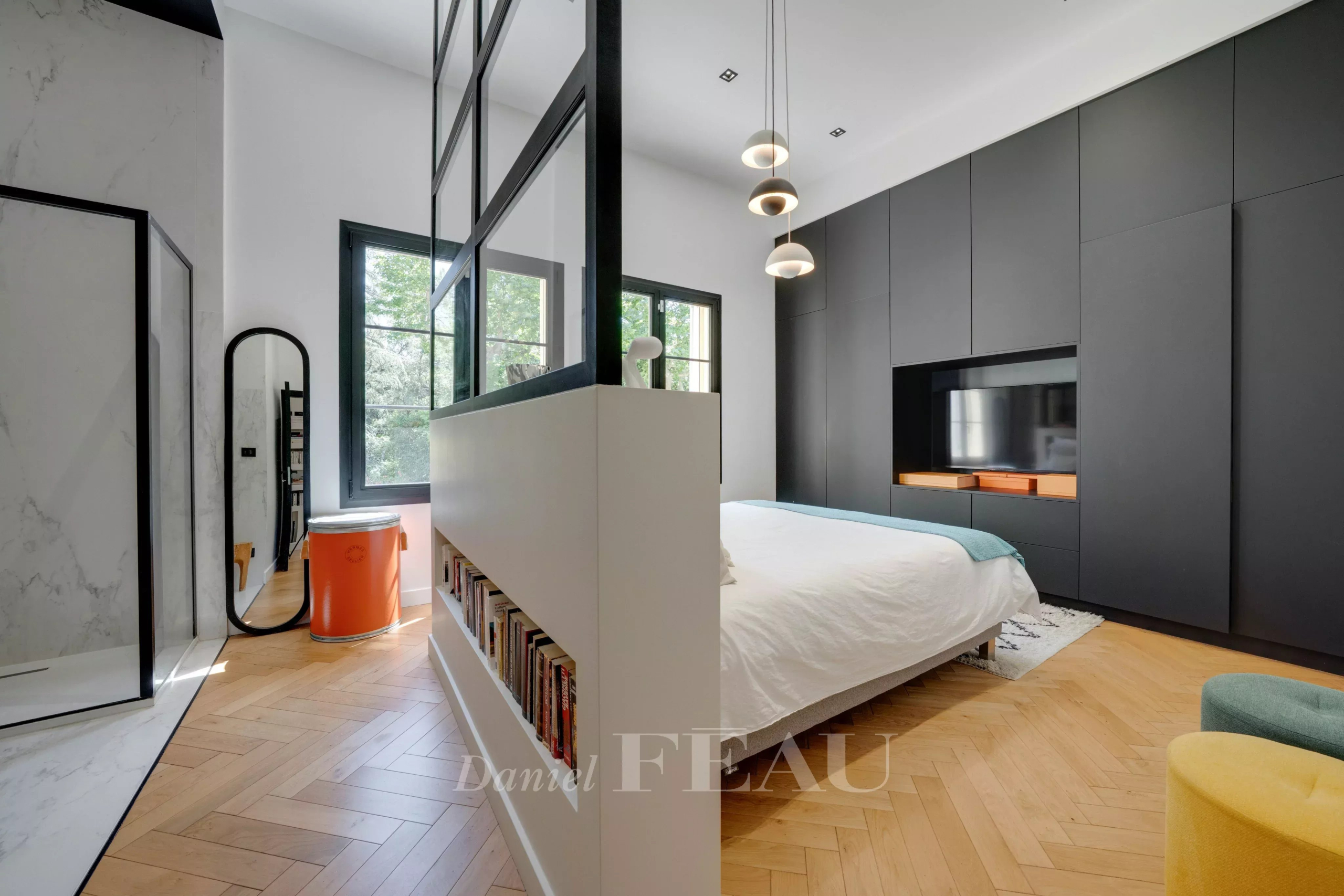 Chambre moderne avec lit, murs noirs et parquet en bois, vue sur la nature à Marseille 9ème.