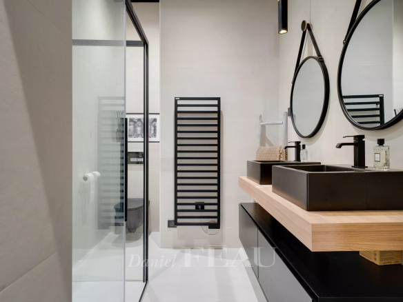 Salle de bain moderne avec douche, double vasque et miroir rond.