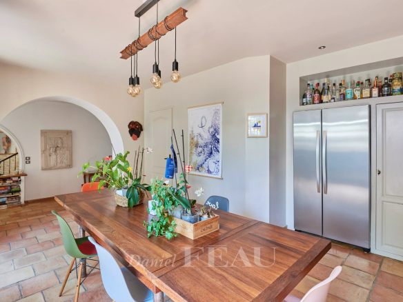 Interior of a charming house with a large wooden table and a stainless steel refrigerator.