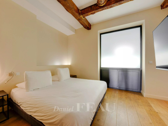 Room in a loft in the Old Port of Marseille with a double bed and exposed beams.