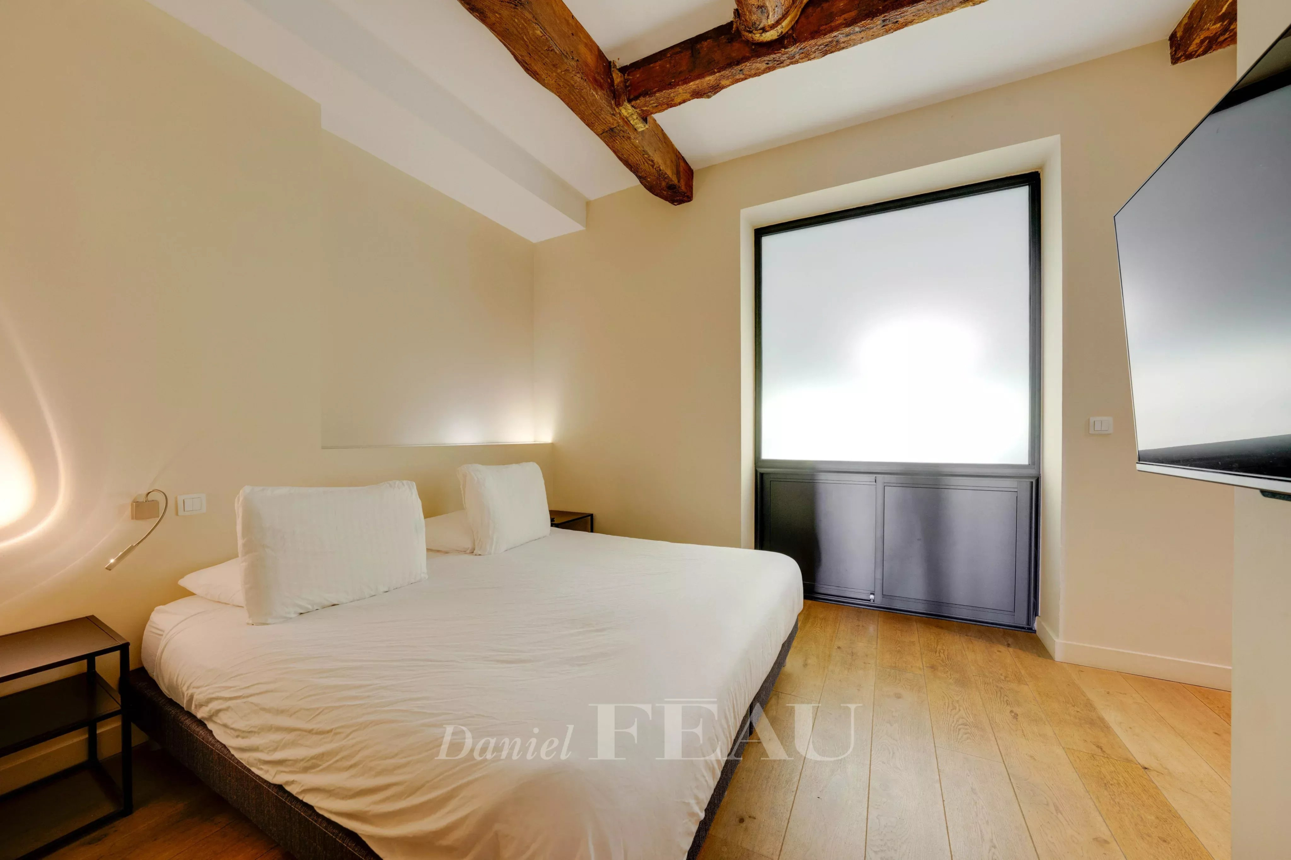 Room in a loft in the Old Port of Marseille with a double bed and exposed beams.