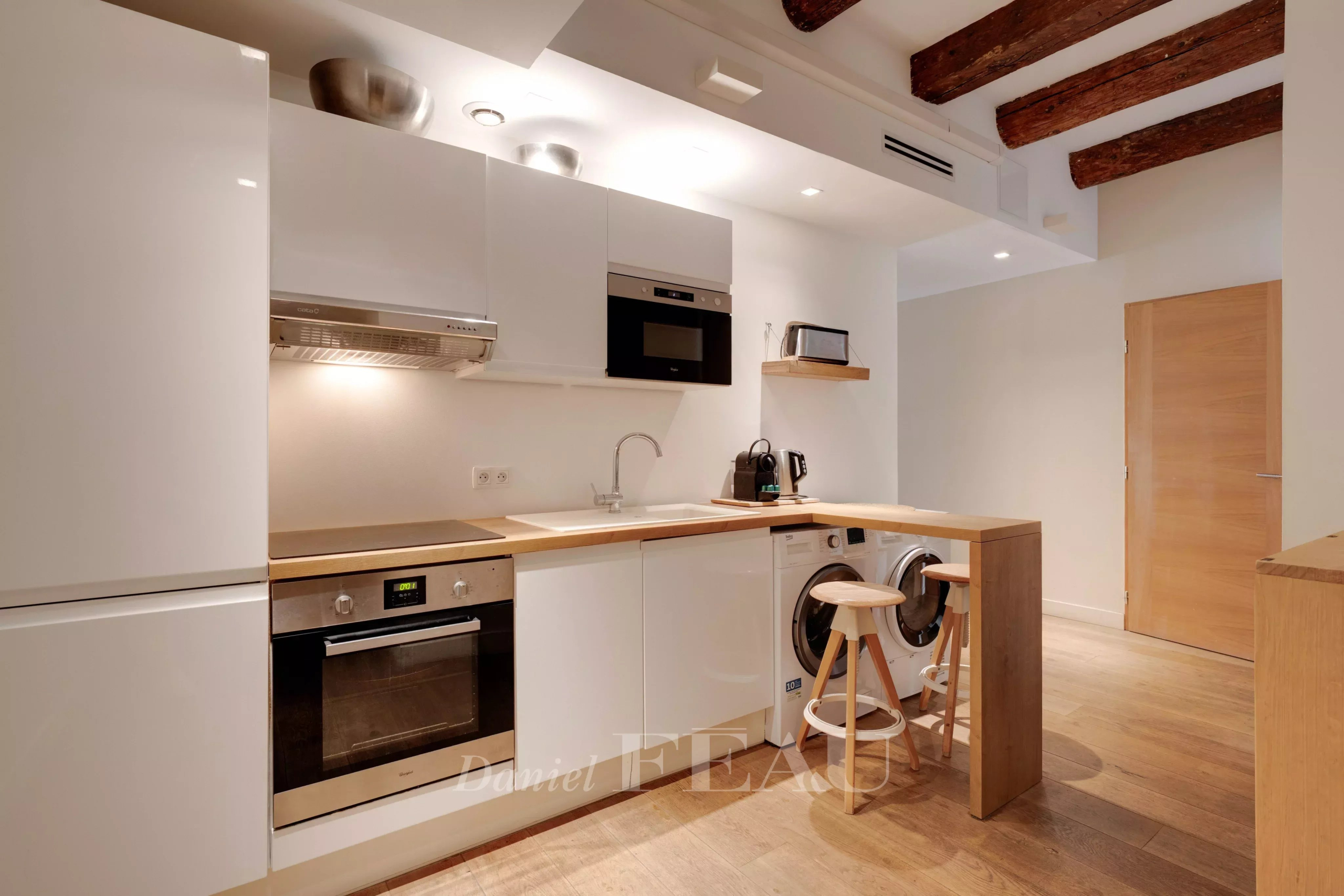 Modern loft kitchen in the Old Port of Marseille with exposed beams.