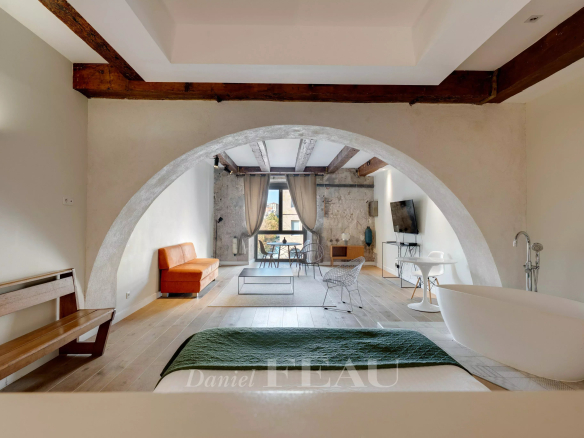 Interior of a loft in the Old Port of Marseille with a bathtub, a sofa and exposed beams.