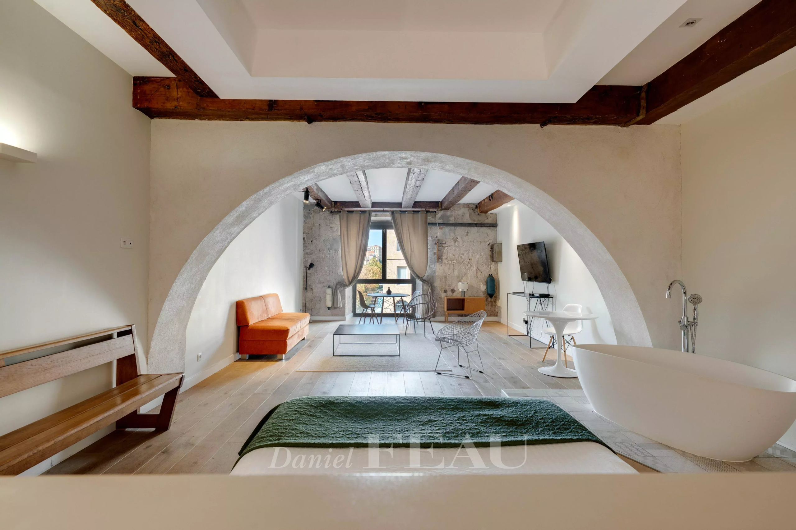 Interior of a loft in the Old Port of Marseille with a bathtub, a sofa and exposed beams.