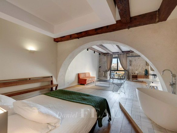 Interior of a loft in the Old Port of Marseille with bed, bathtub and living area.