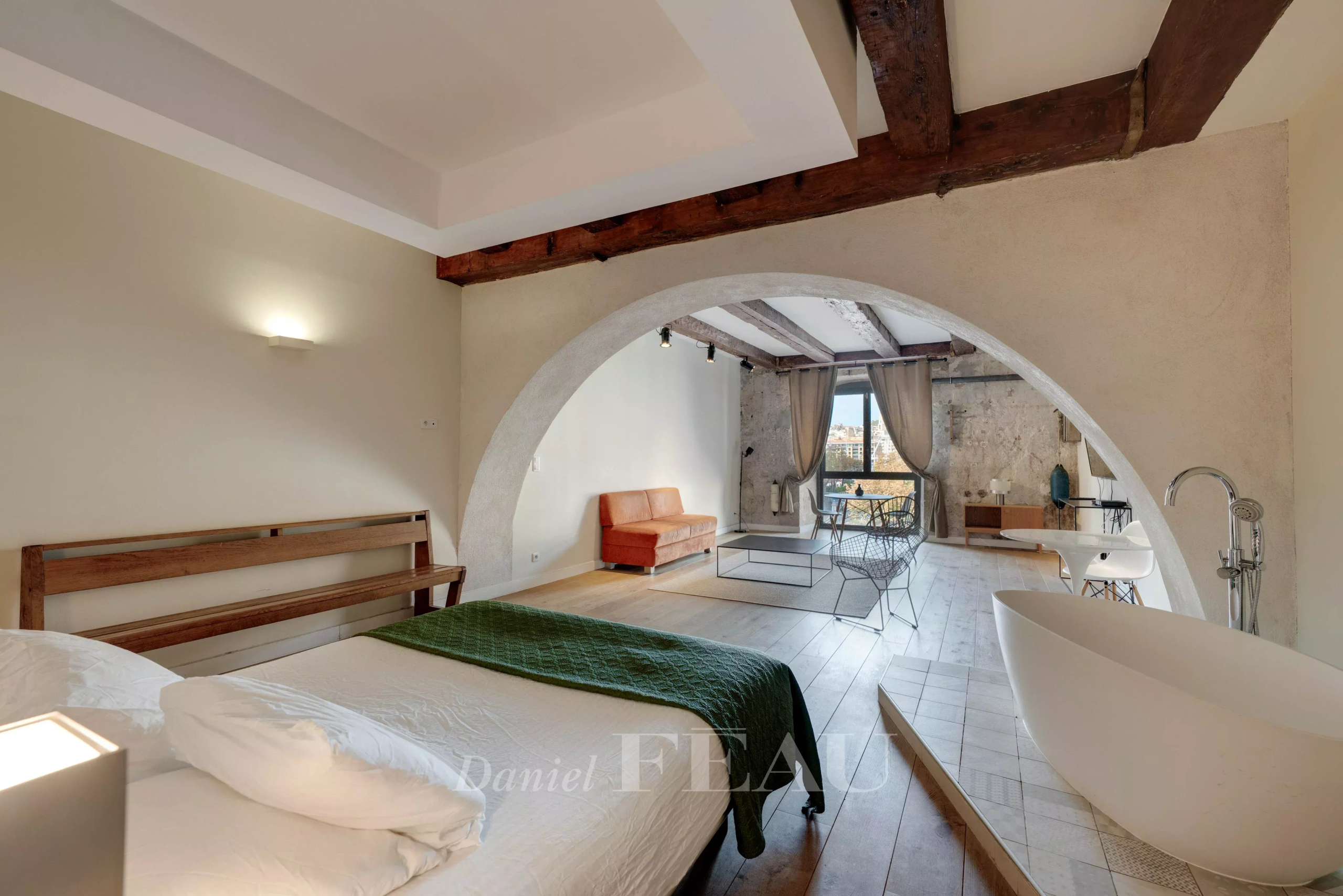 Interior of a loft in the Old Port of Marseille with bed, bathtub and living area.