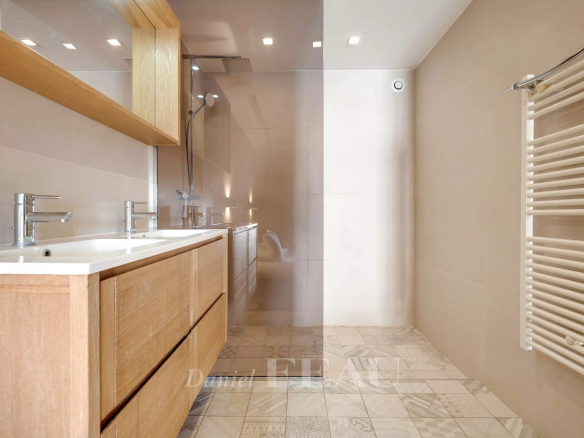 Modern bathroom with wooden furniture and glass shower.