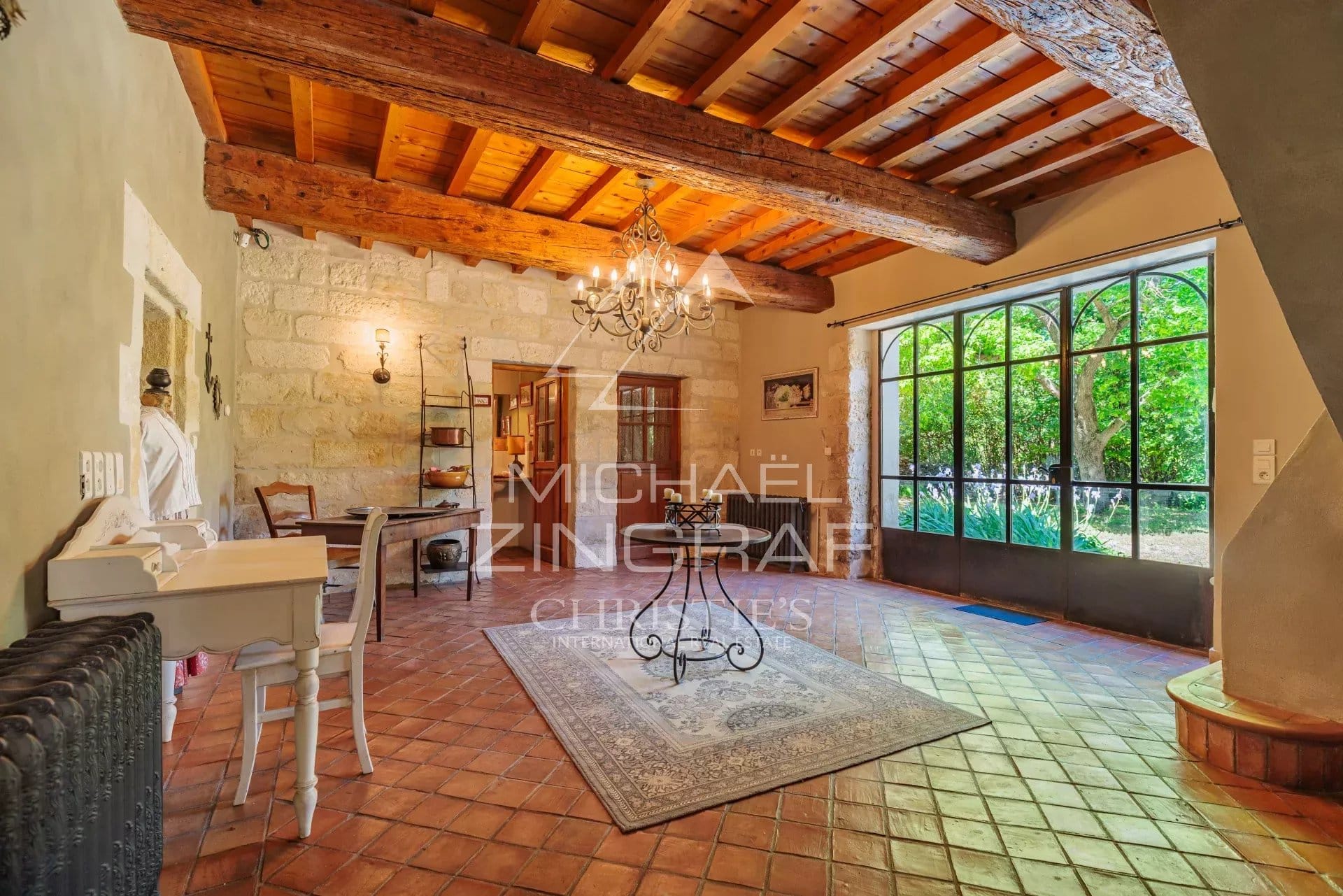 Interior of an old house with wooden beams and tiled floors, natural lighting.