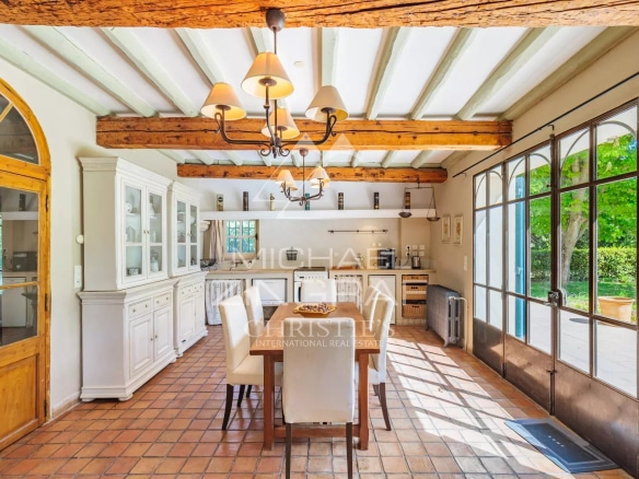 Interior of a bright dining room with exposed beams and large windows.
