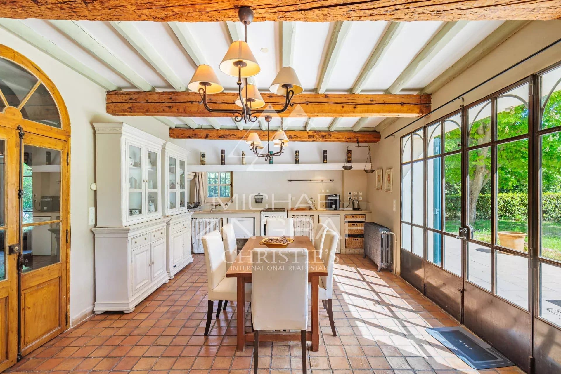 Interior of a bright dining room with exposed beams and large windows.