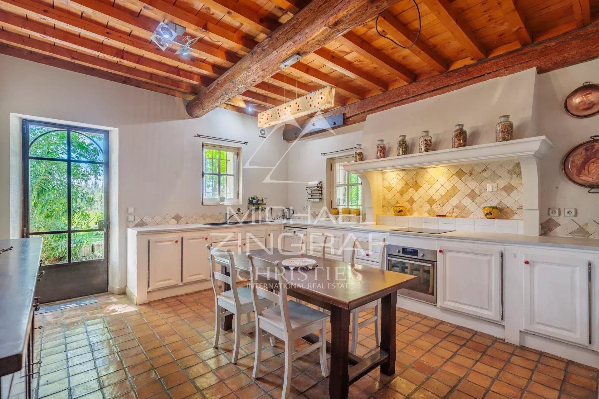 Kitchen in a characterful house with exposed beams and tiled floor, located near Avignon.