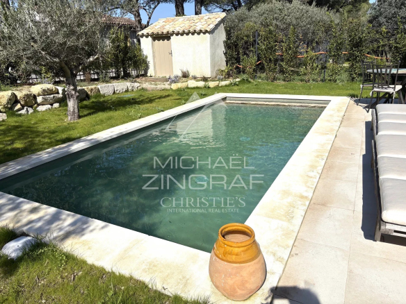 Swimming pool of a villa with garden in Eygalières, surrounded by trees and greenery.
