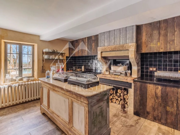 Cuisine d'une maison du 19ème siècle avec un îlot central et une cheminée en pierre.