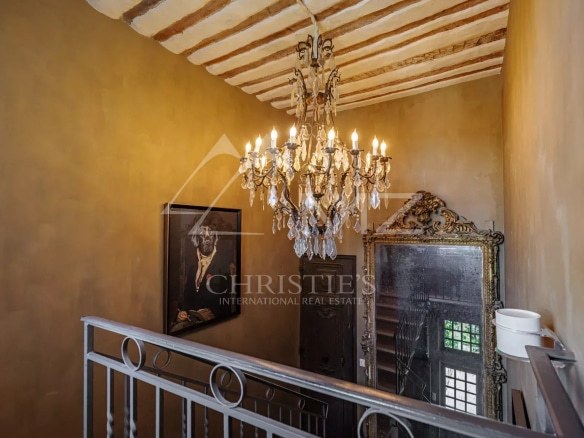 Escalier intérieur d'un hôtel particulier avec un lustre et un miroir ancien.
