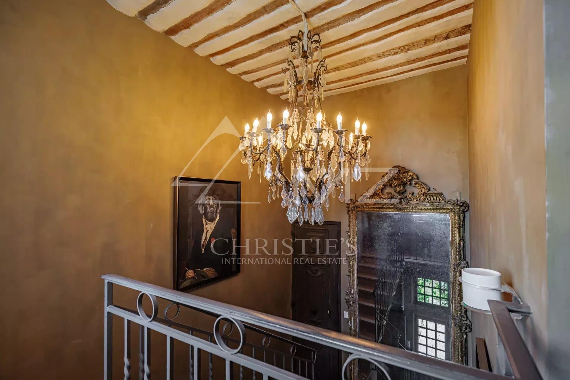 Escalier intérieur d'un hôtel particulier avec un lustre et un miroir ancien.