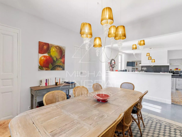 Intérieur d'un mas rénové avec une grande table en bois et des lampes suspendues.