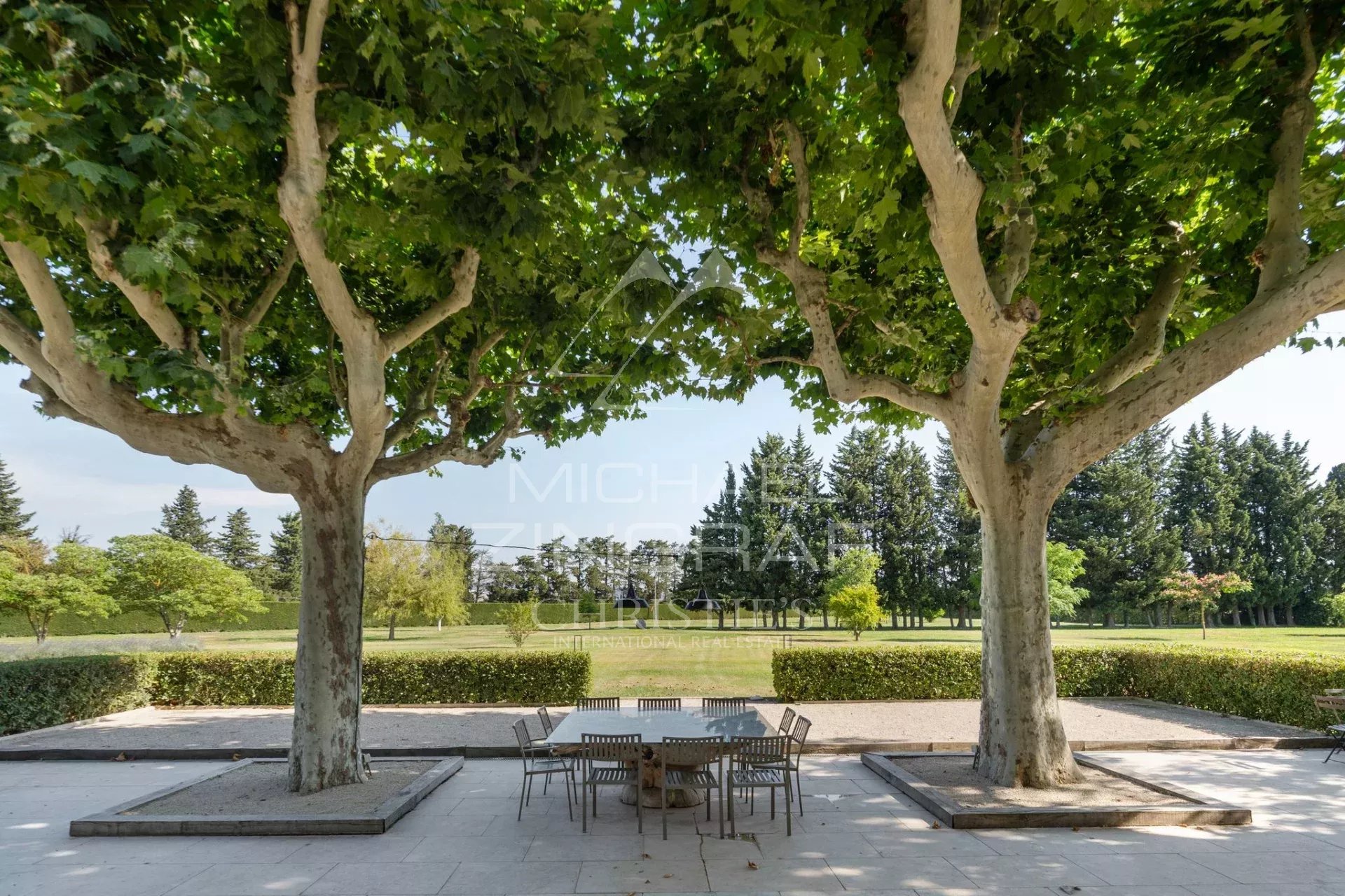 Terrasse d’un mas provençal Terrasse d'un mas rénové avec des platanes et une table en plein air.
