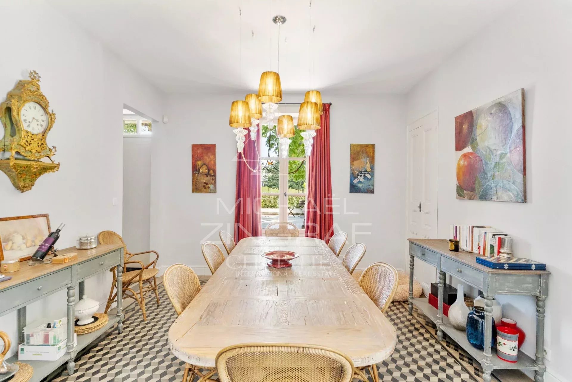 Salle à manger d’un mas rénové Salle à manger d'un mas rénové avec table en bois et chaises en rotin, décorée de tableaux.