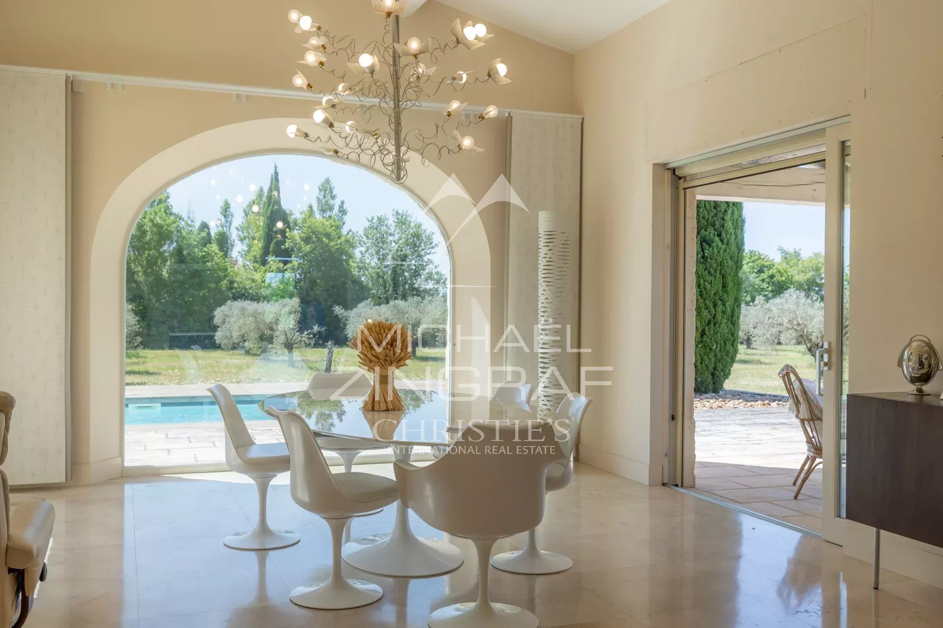 Interior of an exceptional property near Arles Bright interior of a contemporary house with a dining table and white chairs, overlooking the garden.