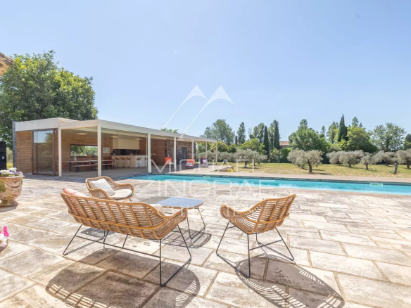 Terrace with rattan chairs and swimming pool, overlooking the garden with olive trees.