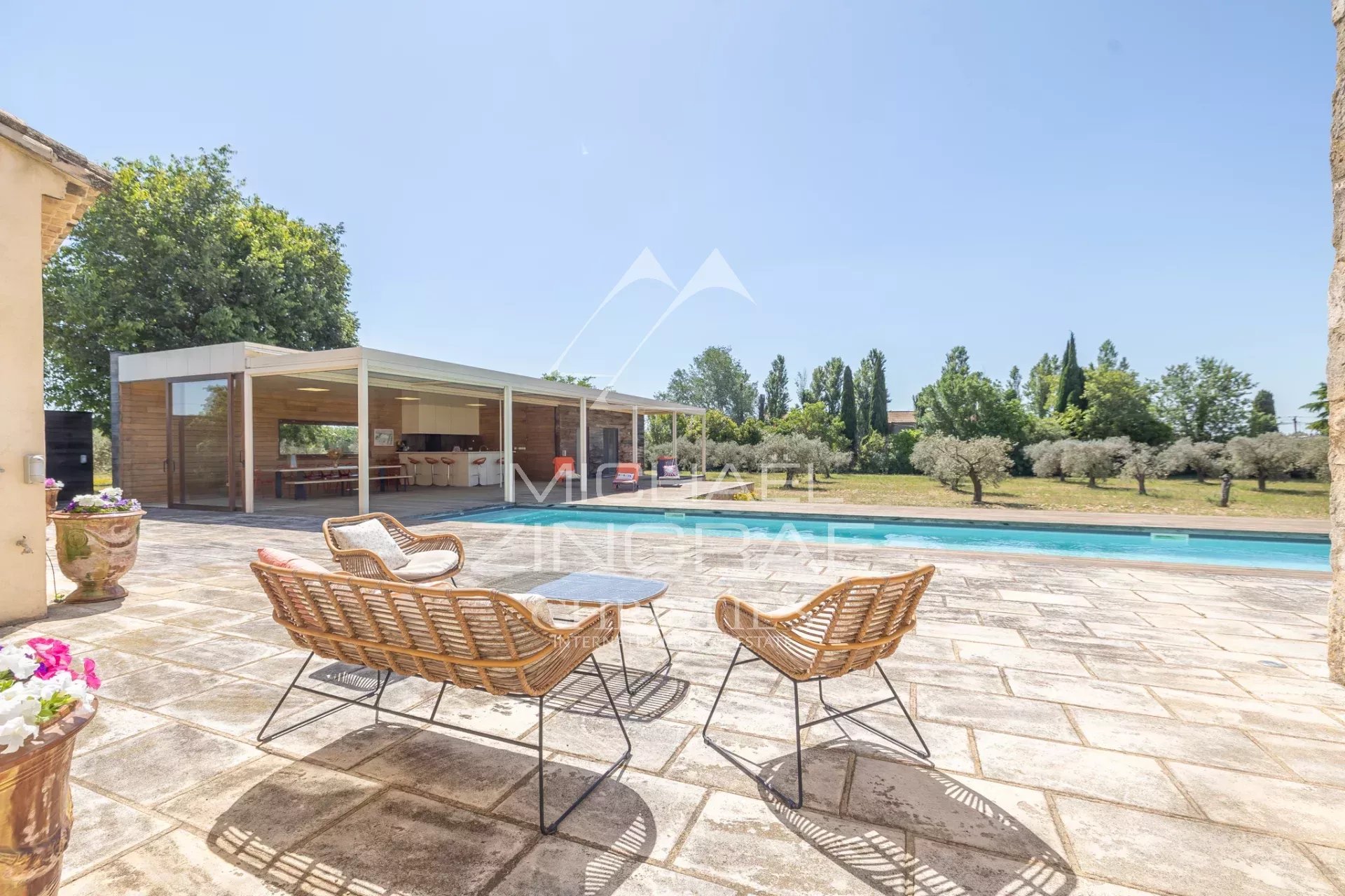 Exceptional property near Arles Terrace with rattan chairs and swimming pool, overlooking the garden with olive trees.