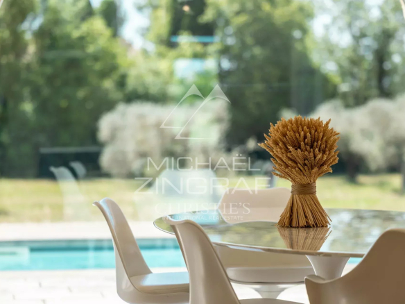 Modern table with a bouquet of wheat in a bright house, overlooking a garden with a swimming pool.