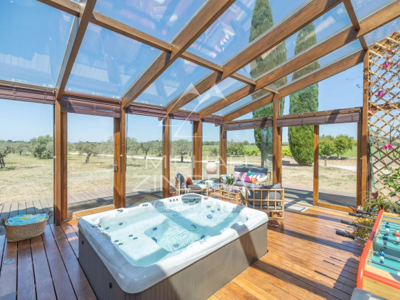Relaxation area with jacuzzi and wooden lounge, surrounded by greenery.